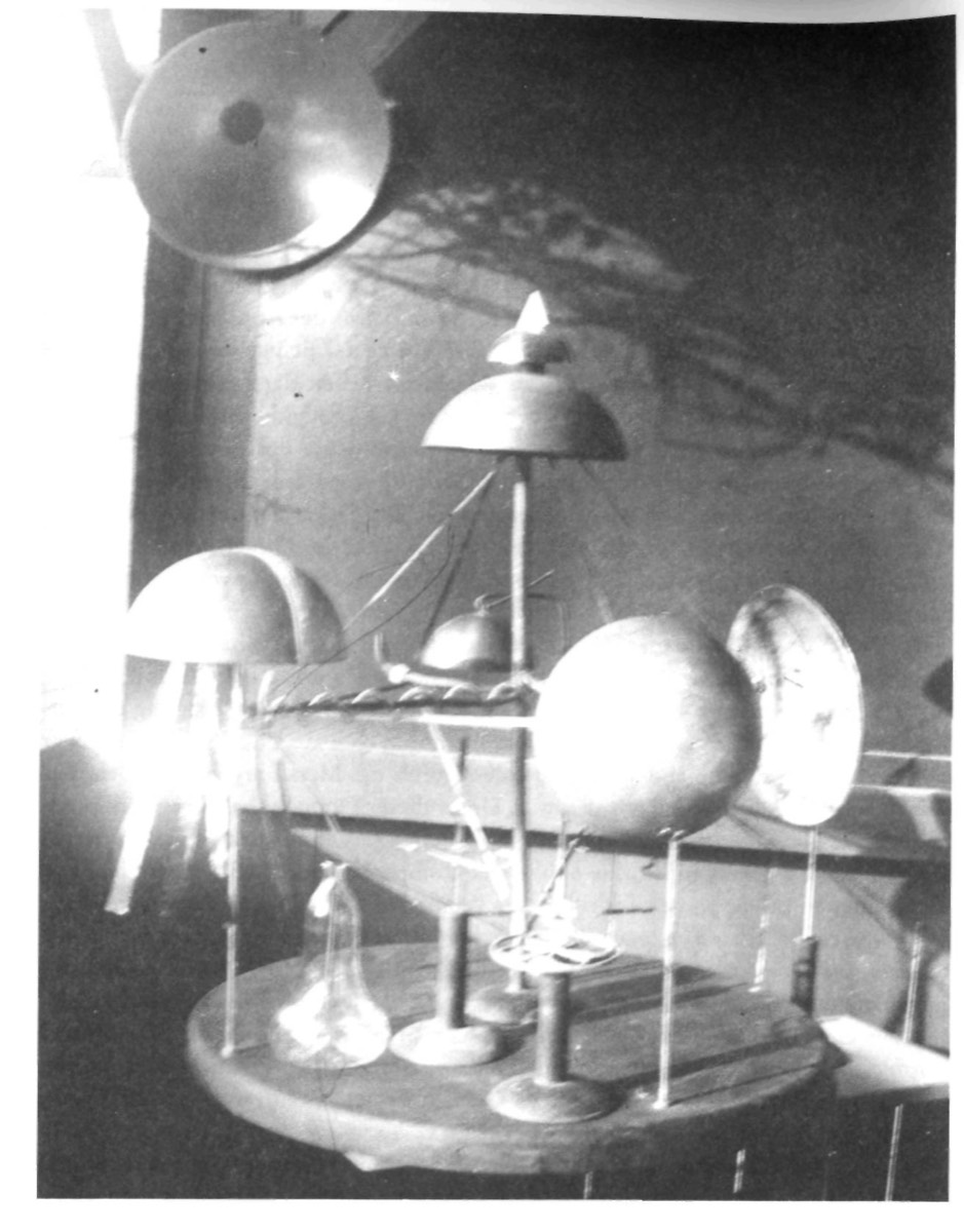 Period photograph of the Strader apparatus stage model: hemispheres and twisted rods on a round table with a glass retort.